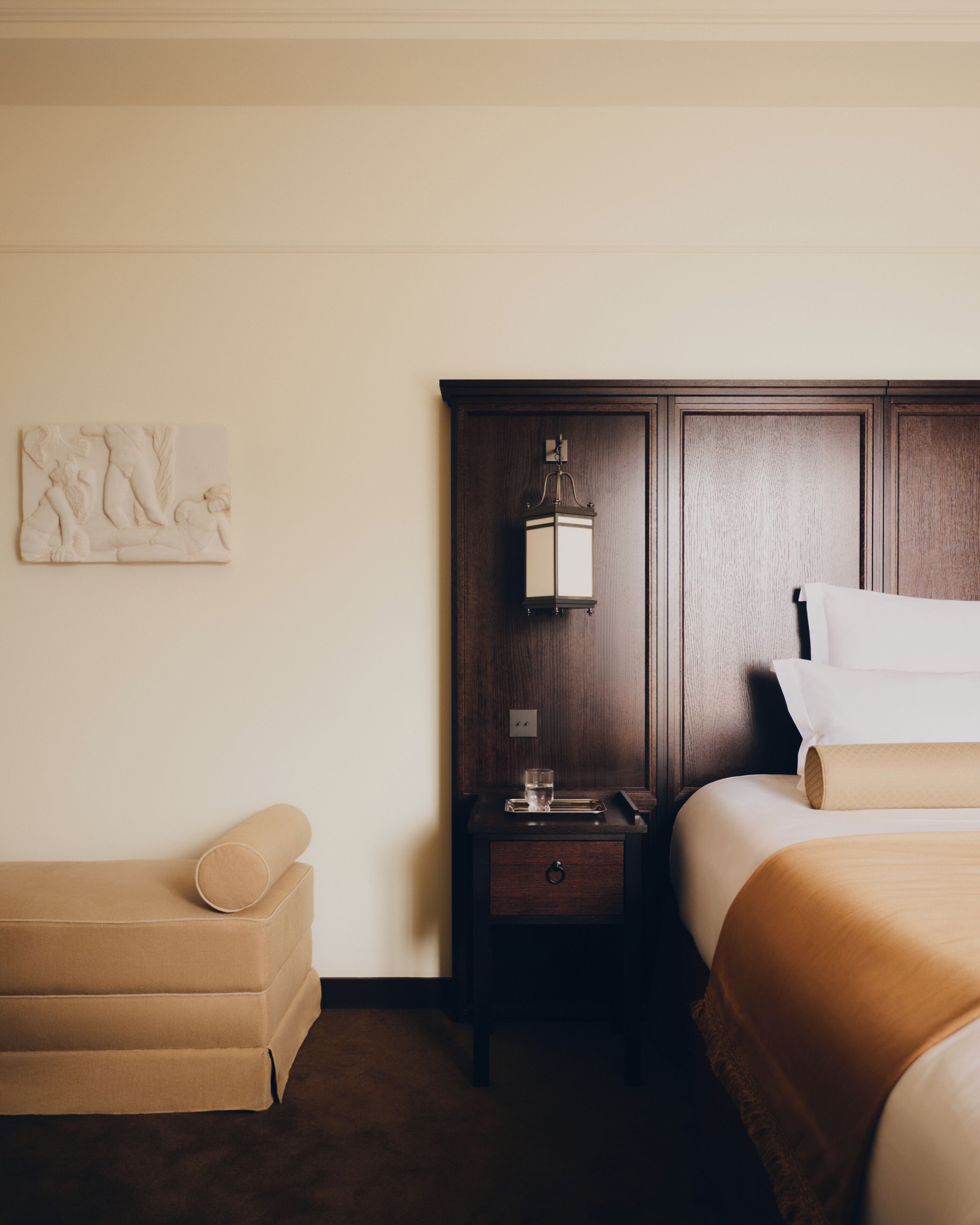 Una habitación de hotel con una cama, mesita de noche, lámpara, obras de arte y un sofá.