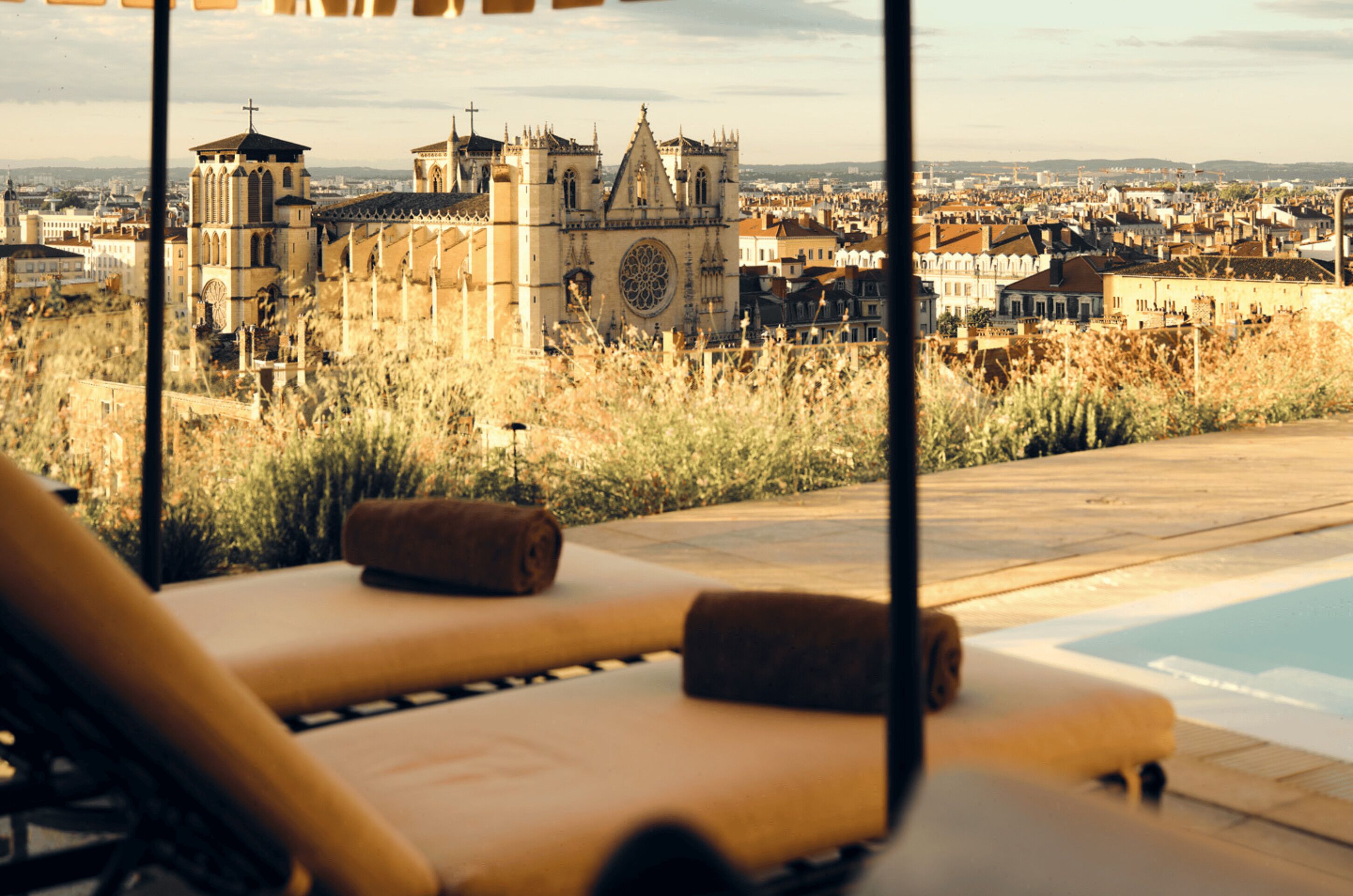 Habitación de hotel con piscina, sillones de descanso y vistas a un edificio histórico.