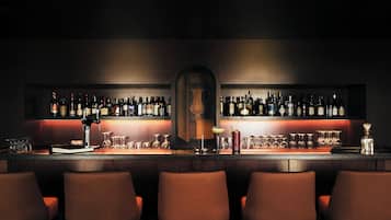 A bar with multiple shelves of bottles, glasses, and a central bar counter.