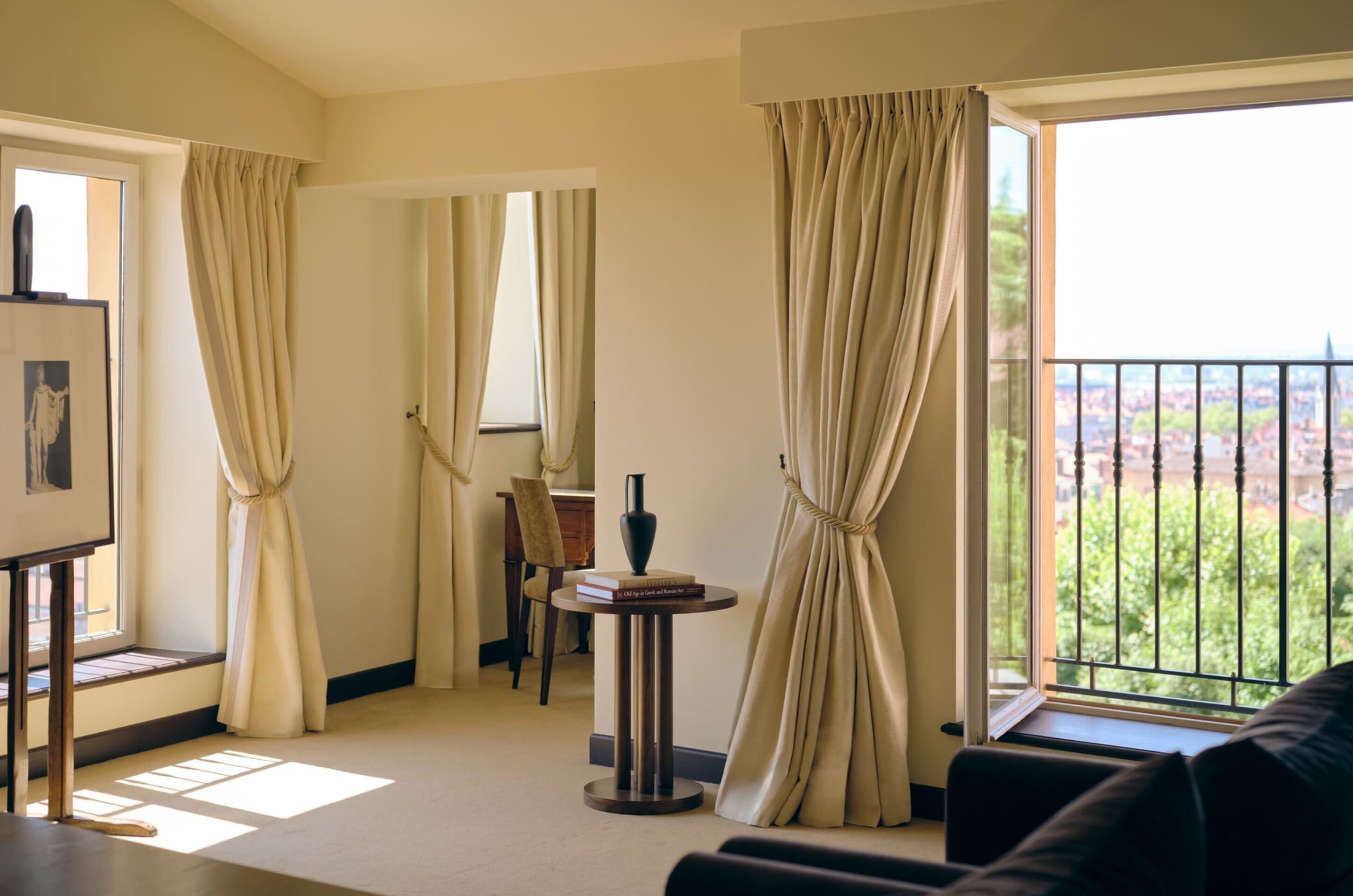 Una habitación de hotel con balcón, comedor y un cuadro en la pared.