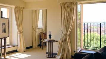 Una habitación de hotel con balcón, comedor y un cuadro en la pared.