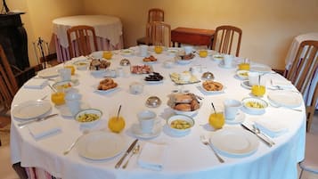 A round dining table set for breakfast with various dishes, drinks, and utensils.