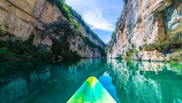A narrow canyon with a kayak in the foreground, surrounded by steep cliffs and clear water.