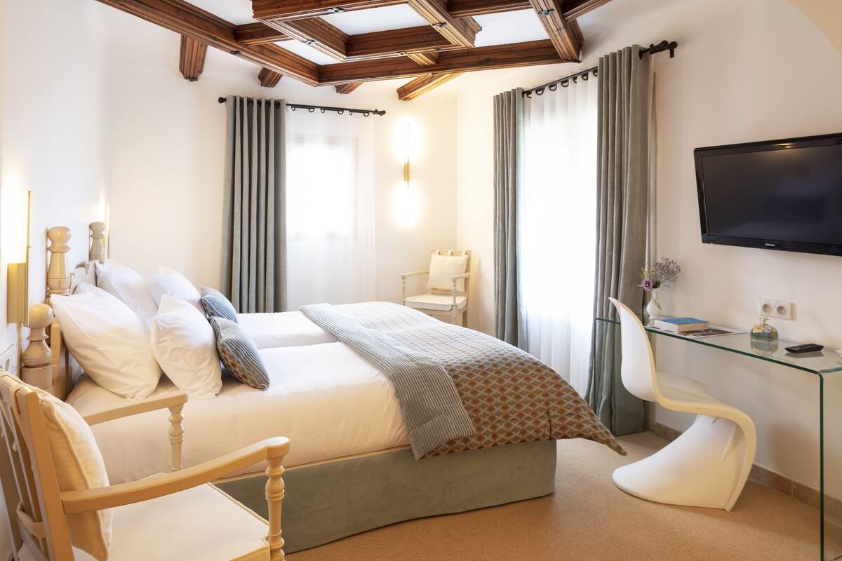 Una habitación de hotel moderna con una cama grande, un escritorio, una silla y un televisor.
