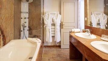 Une salle de bain avec une baignoire, deux lavabos, une douche et un miroir.