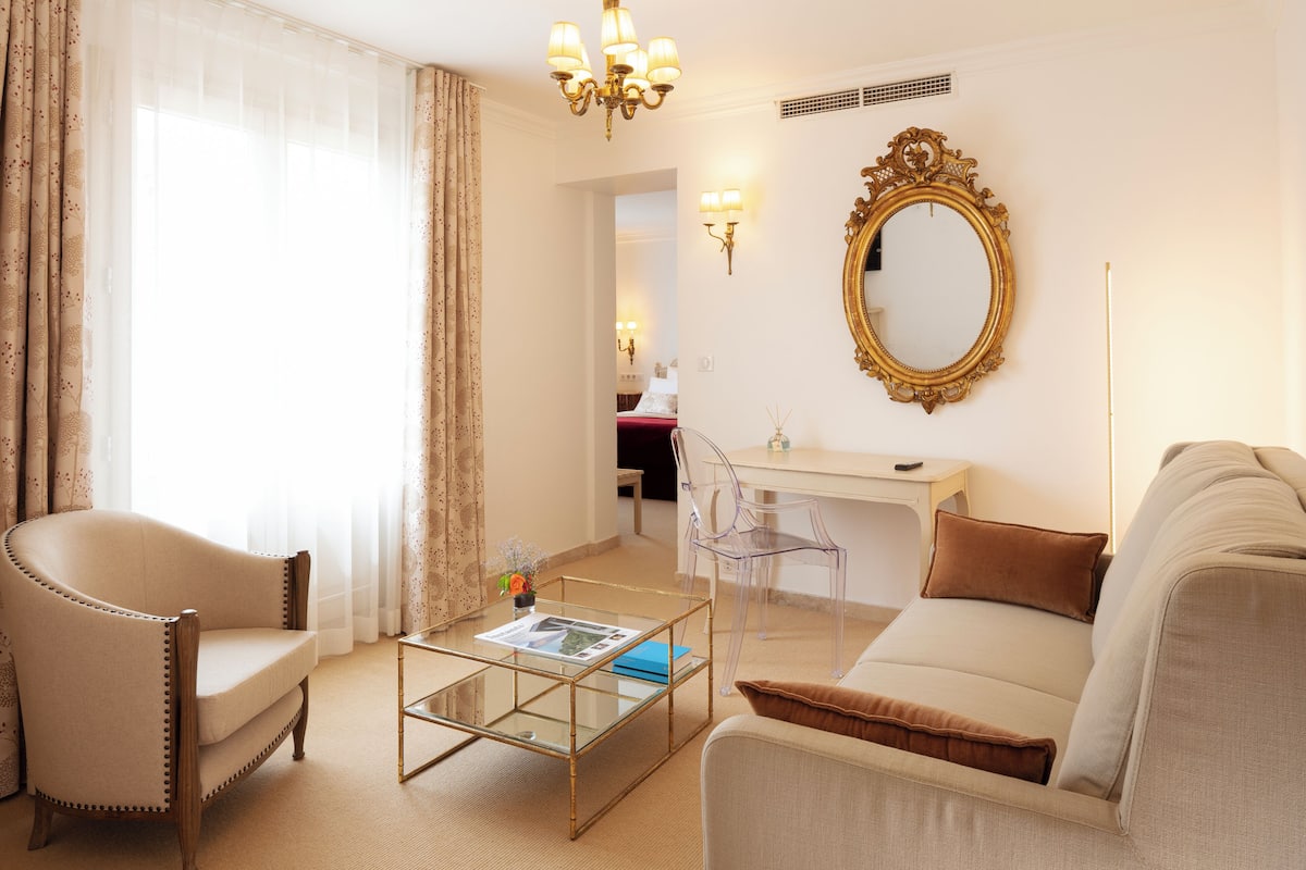 Una sala de estar con sofá, sillón, mesa de centro de vidrio y un escritorio con silla.