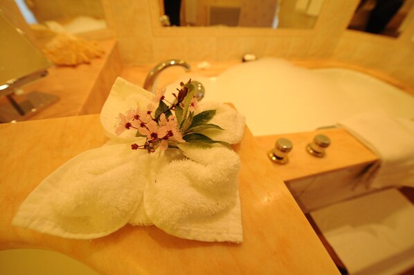 Un baño con lavamanos, espejo y toalla con flores.