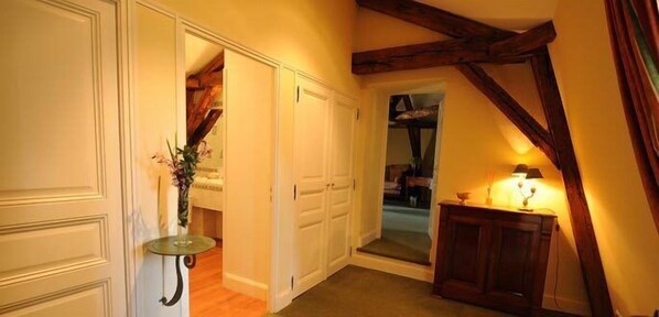A hallway with white doors, a glass table with a vase, and a wooden cabinet with a lamp.