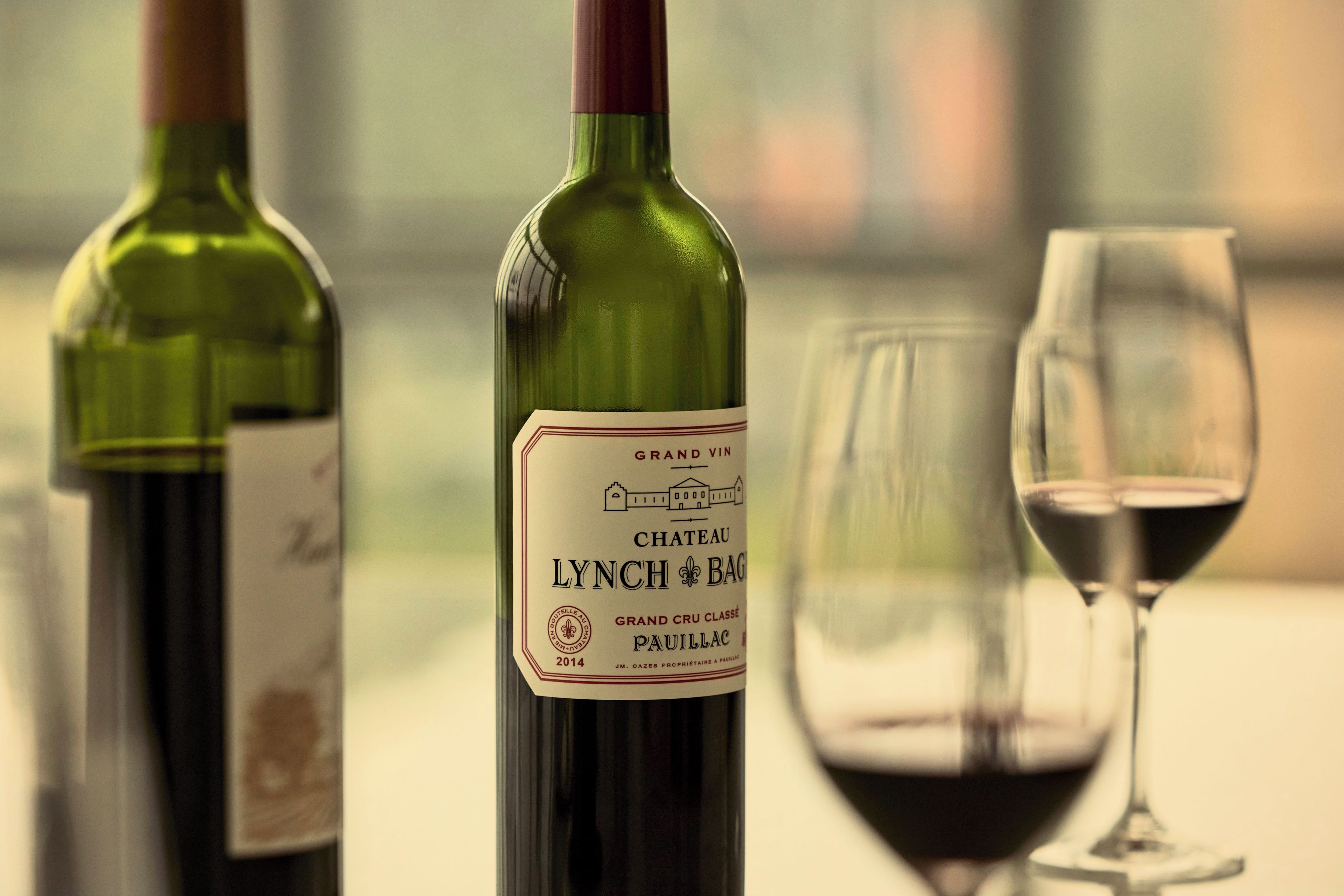 Two wine bottles and a wine glass on a table.