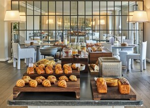 A breakfast buffet with pastries, a coffee station, and seating arrangements. - COMO Cordeillan‑Bages (Pauillac)