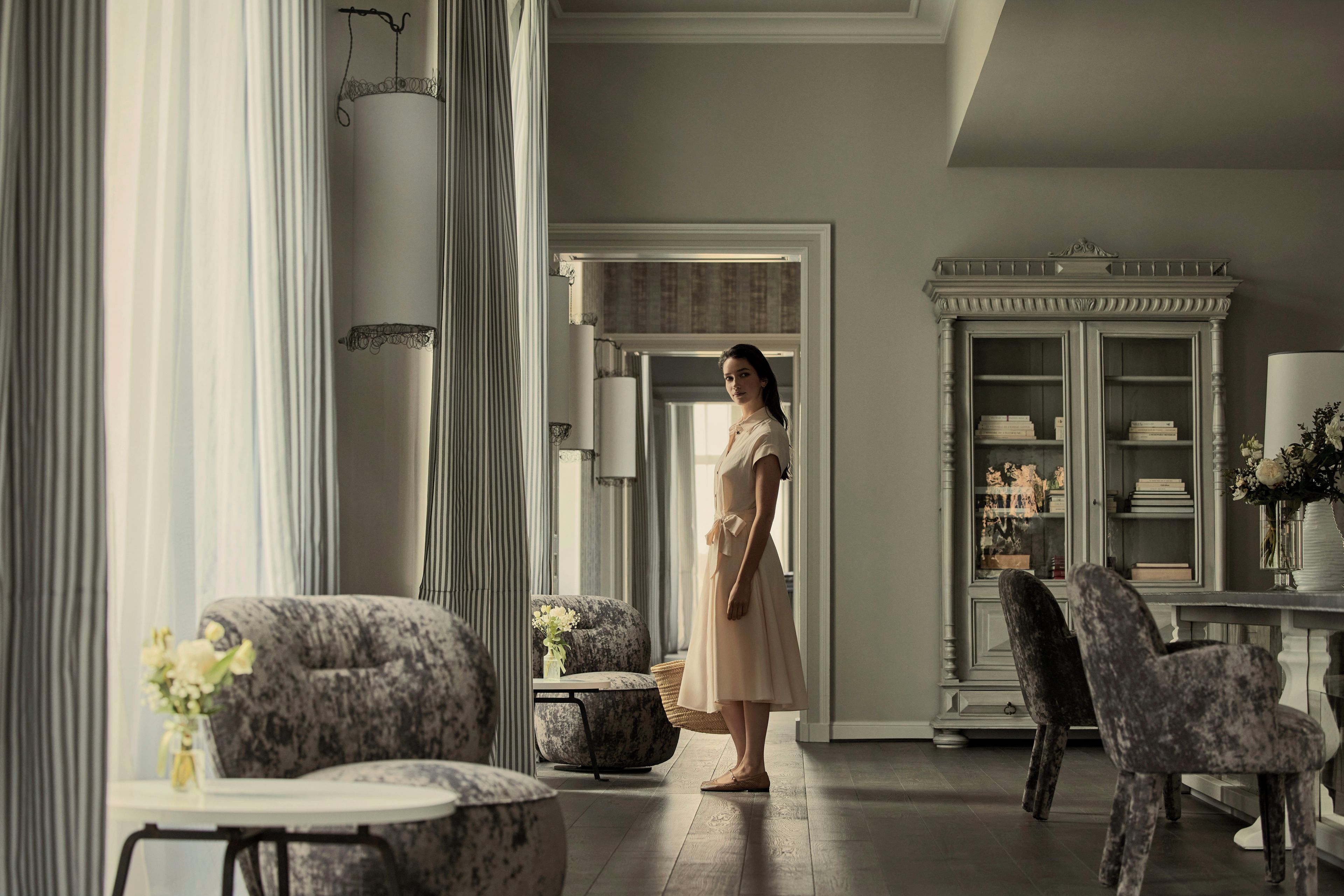 A spacious room with a large window, a fireplace, and a seating area with chairs and a table.