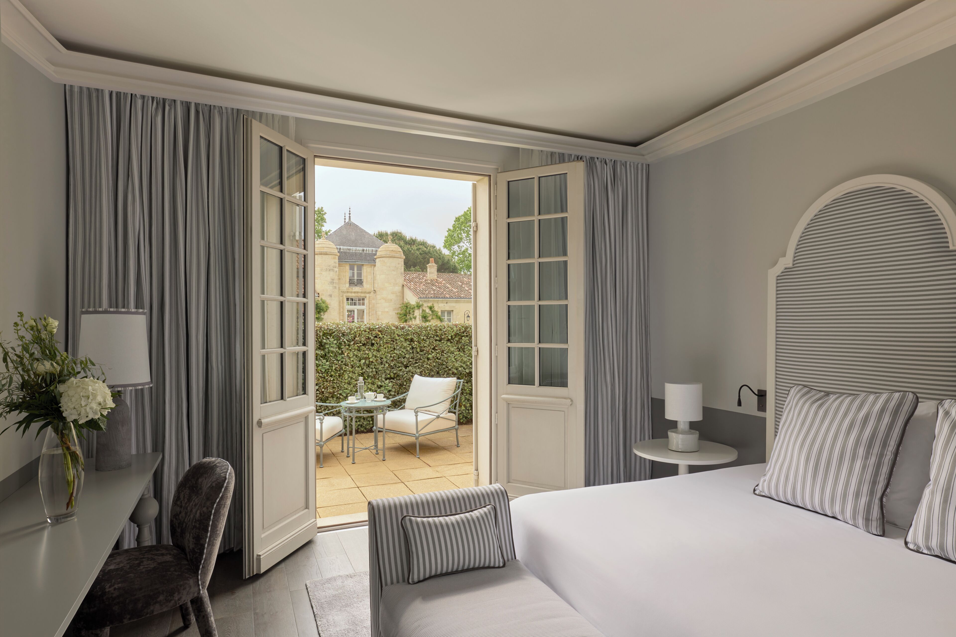 Una camera d'albergo con un letto, una scrivania, una sedia, un tavolino e vista all'esterno.