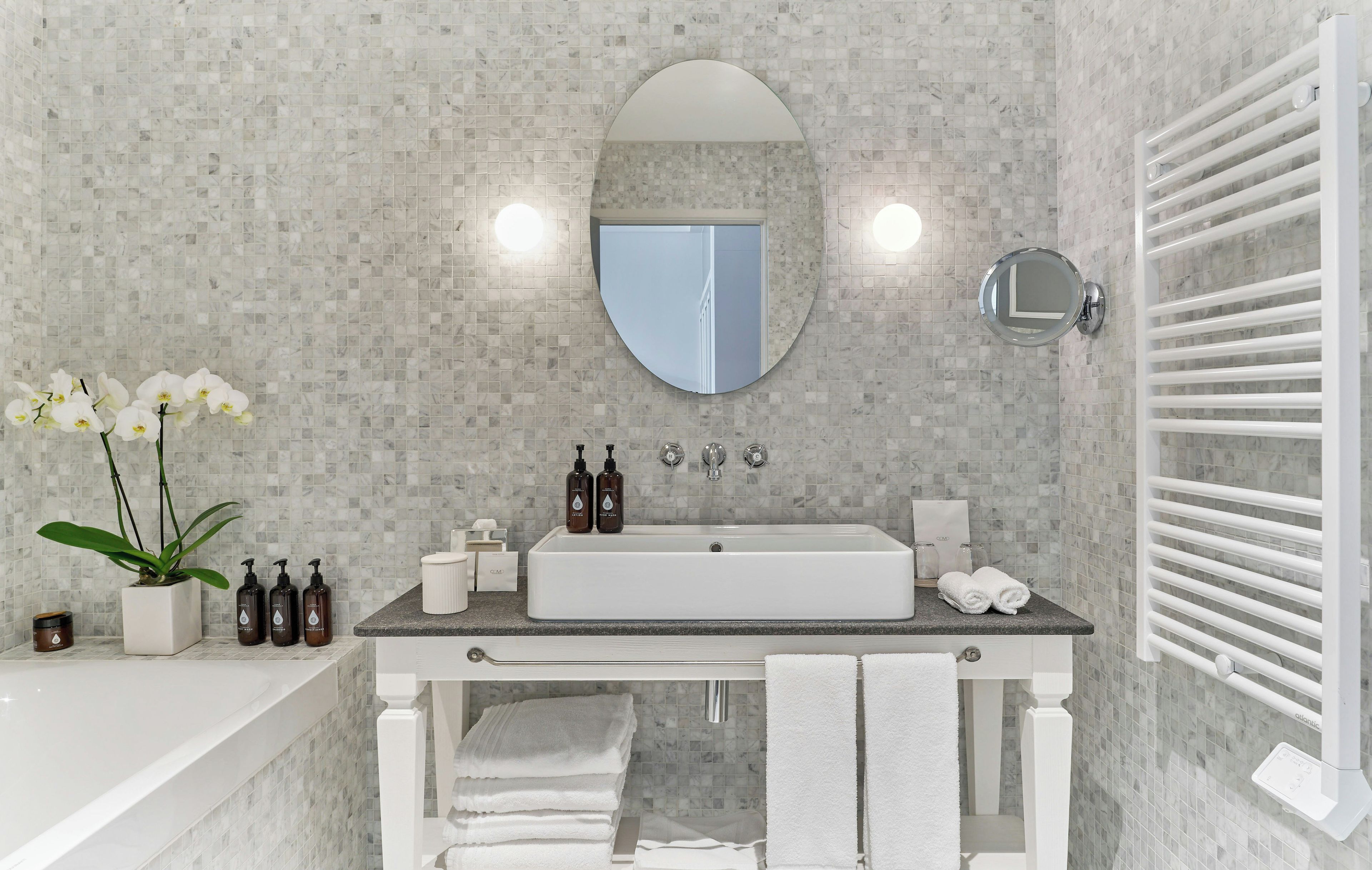 A modern bathroom with a rectangular sink, a large mirror, and a towel rack.