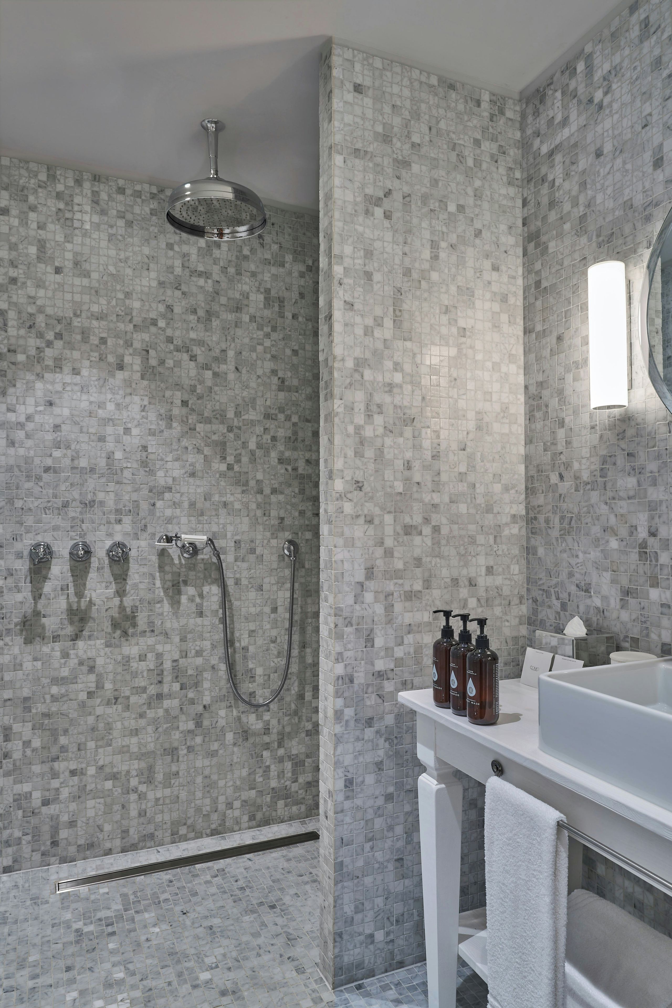 A modern bathroom with a shower, a sink, and toiletries.