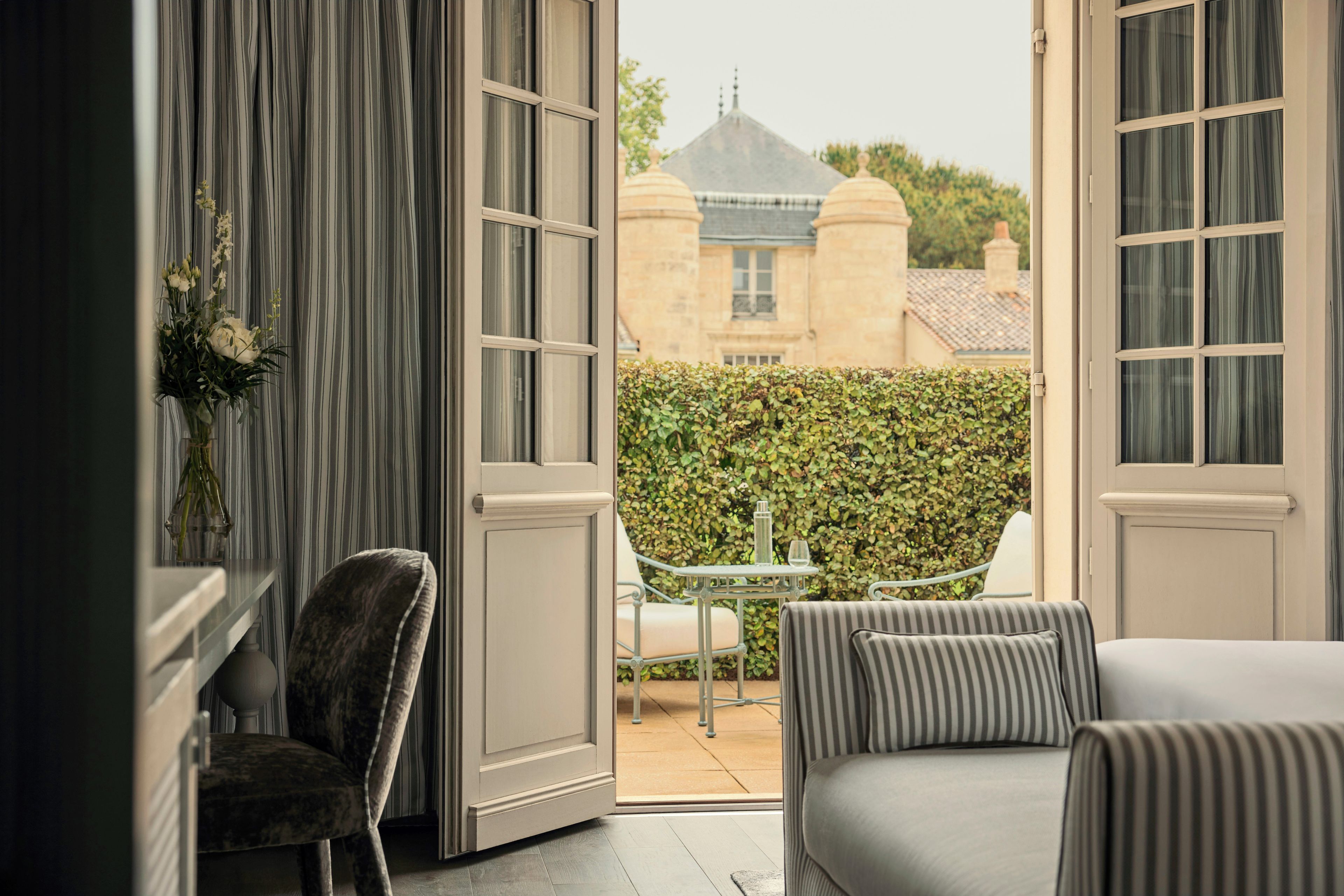 An open balcony with a view of a building, a table with chairs, and a sofa.