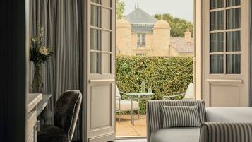 An open balcony with a view of a building, a table with chairs, and a sofa.