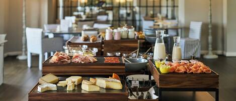 Una mesa de buffet con diversos quesos, embutidos y condimentos.
