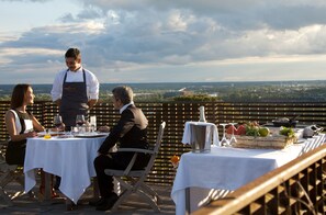 Restaurante com área externa, um garçom e uma mesa posta para dois.