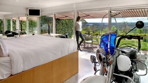 Un dormitorio con una cama grande, una motocicleta y vistas al campo.