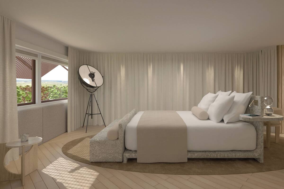 A modern bedroom with a large bed, a bedside table, a floor lamp, and a view of greenery outside.