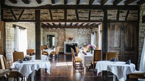 A dining area with stone walls, wooden beams, and tables set for dining. - Château de Marçay (Marcay)