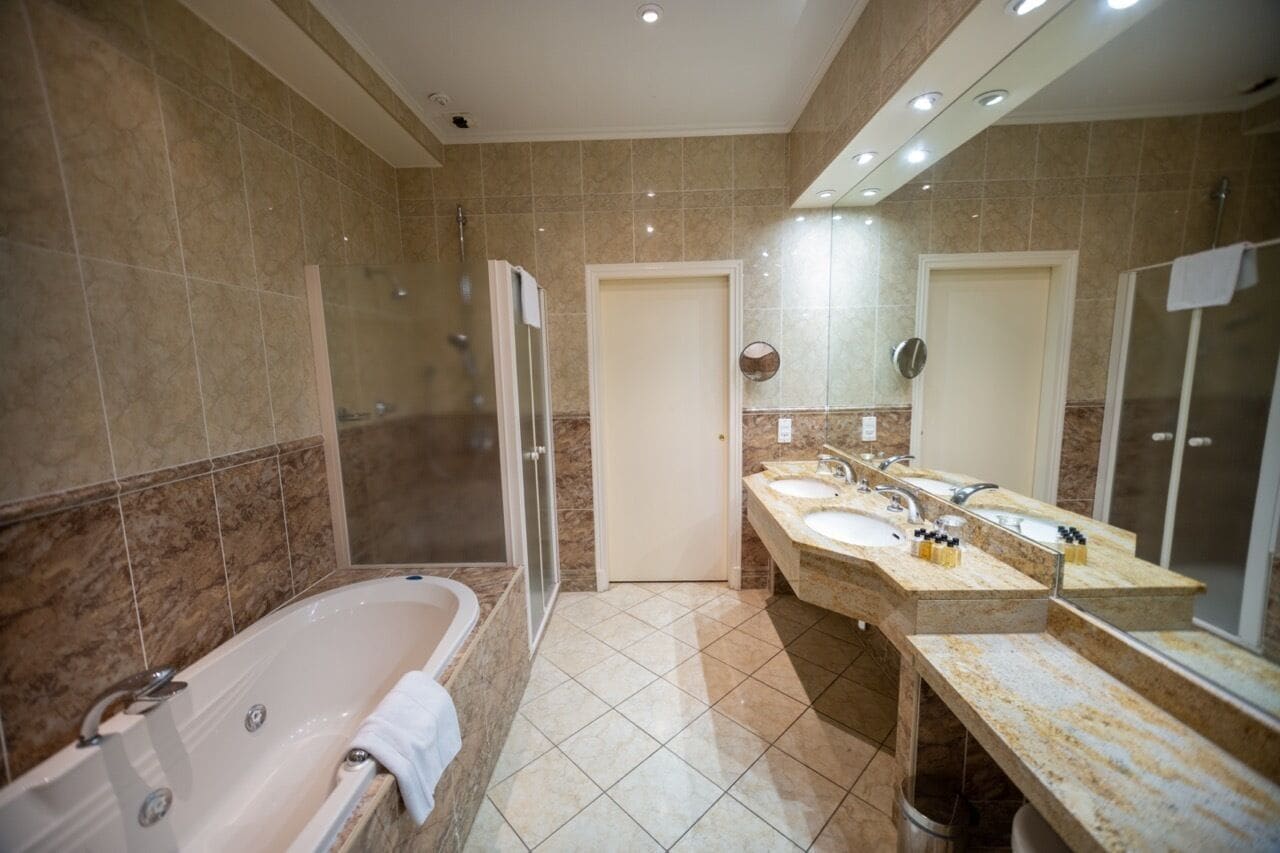 A modern bathroom with a large bathtub, a walk-in shower, and a vanity with two sinks.