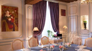 A dining room with a table set for six, featuring a blue tablecloth, floral centerpieces, and a piano in the background. - Château de Noizay (Noizay)