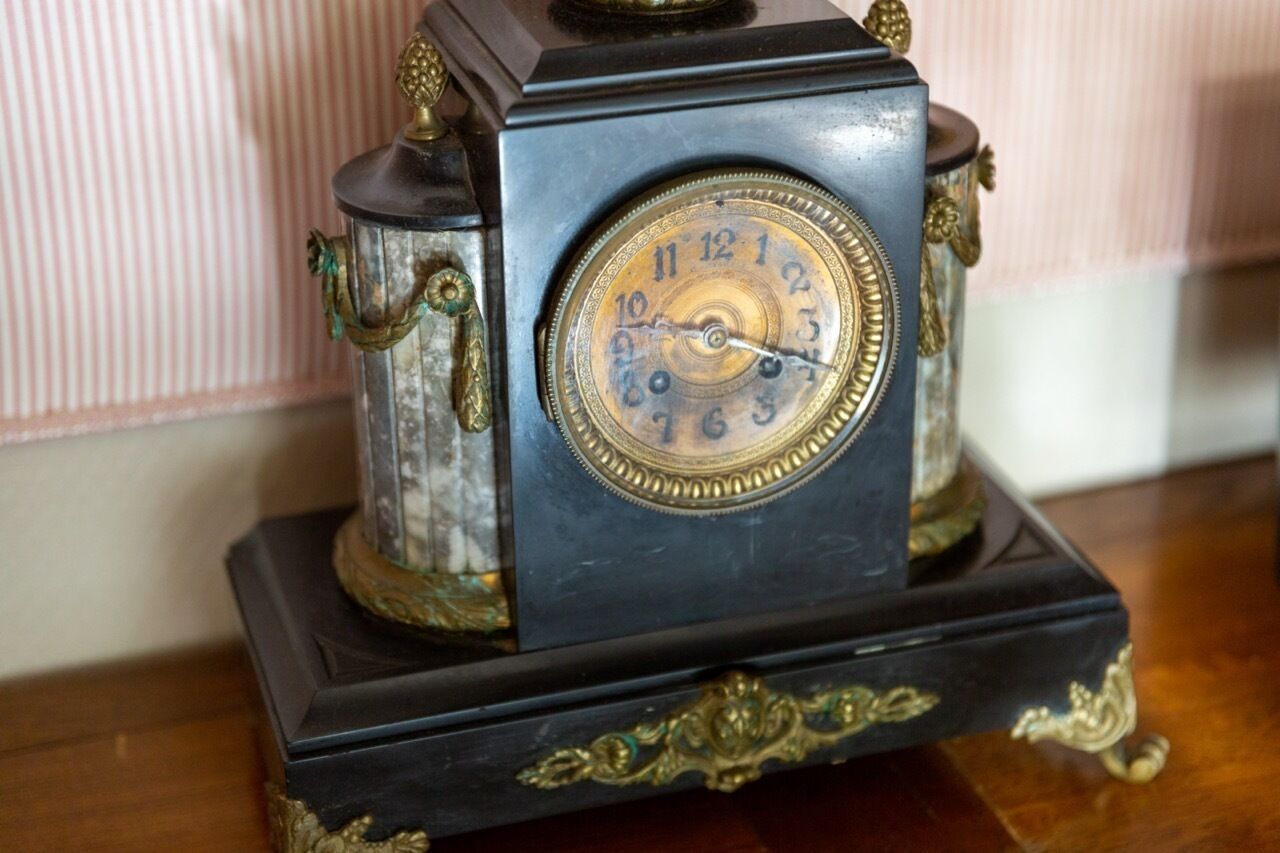 Une horloge ancienne, ornée de sculptures complexes et dotée d’un socle sombre.