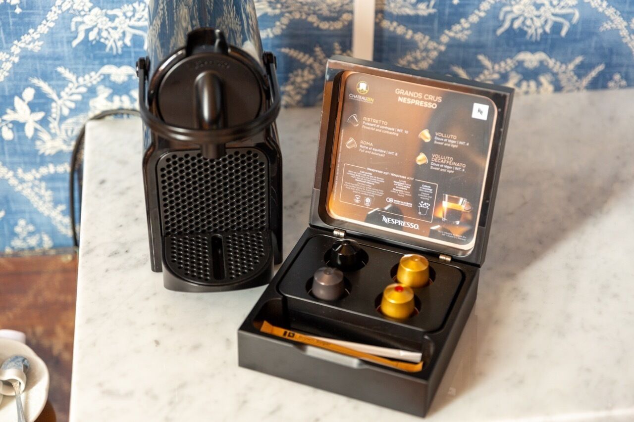 A Nespresso coffee machine with its lid open, revealing the coffee pod compartment and control buttons.