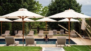 A swimming pool area with lounge chairs and umbrellas.