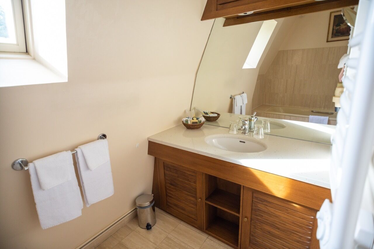 A bathroom with a double sink, wooden cabinets, a mirror, and a towel rack.