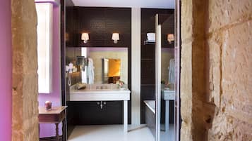 A modern bathroom with a white sink, dark tiled walls, and a glass shower enclosure.