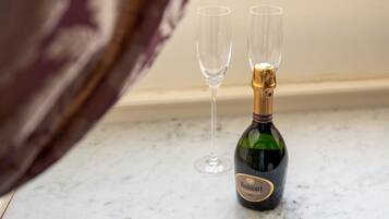 A bottle of Ruinart champagne and two empty glasses on a marble countertop.