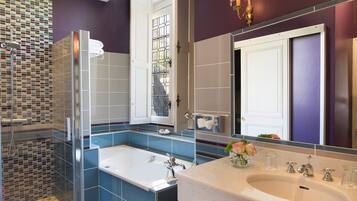 A modern bathroom with a glass shower enclosure, a large bathtub, and a vanity with a sink and mirror.