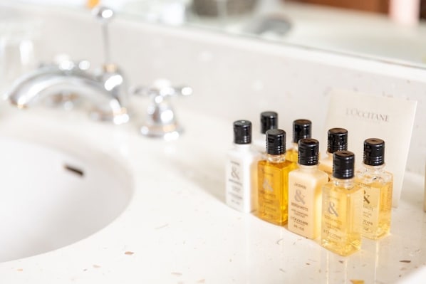 A bathroom sink with multiple bottles of perfume and a mirror. - Château de Noizay (Noizay)