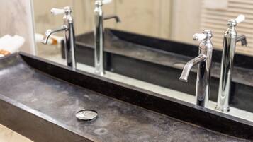 A bathroom with a black countertop, three chrome faucets, and a mirror reflecting the sink area.