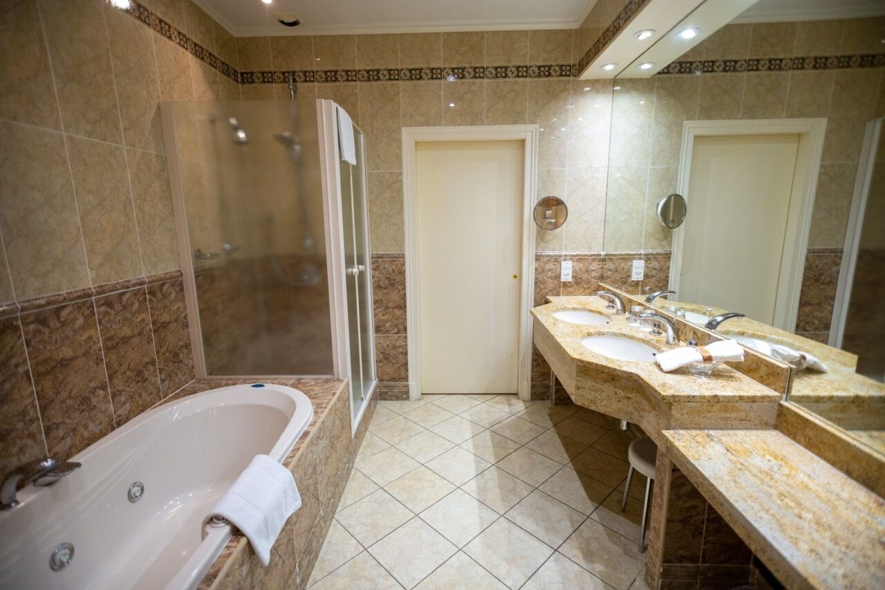 Une salle de bain avec une baignoire, deux lavabos, une douche et une porte.
