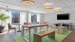 Une salle de conférence moderne, dotée d’une grande table, de bancs et d’un écran de télévision.