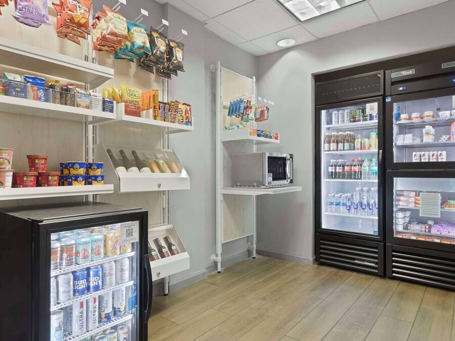 A self-service beverage station with refrigerated drink dispensers and shelves stocked with snacks and beverages.
