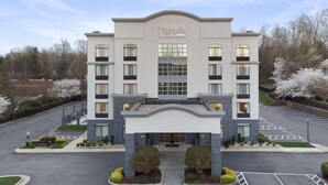 Un hôtel moderne doté d’une entrée principale, de plusieurs étages et d’un parking.