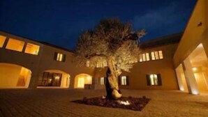 A building with a central courtyard featuring a tree, multiple windows, and a paved walkway. - Domaine de Saint Endréol Golf & Spa Resort**** (La Motte)