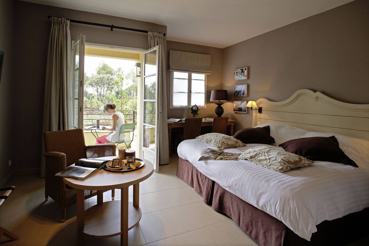 Habitación de hotel con cama, escritorio, silla y mesa con una bandeja de alimentos para el desayuno.