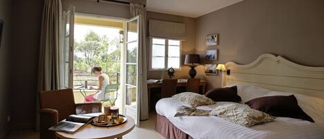 Quarto de hotel com uma cama, uma escrivaninha, uma cadeira e uma mesa com uma bandeja de itens de café da manhã.