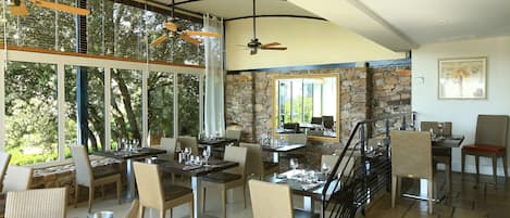 Un comedor espacioso con techos altos, ventanas amplias y una pared de acento de piedra.