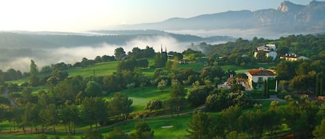 Un campo de golf con un club de campo y árboles circundantes.