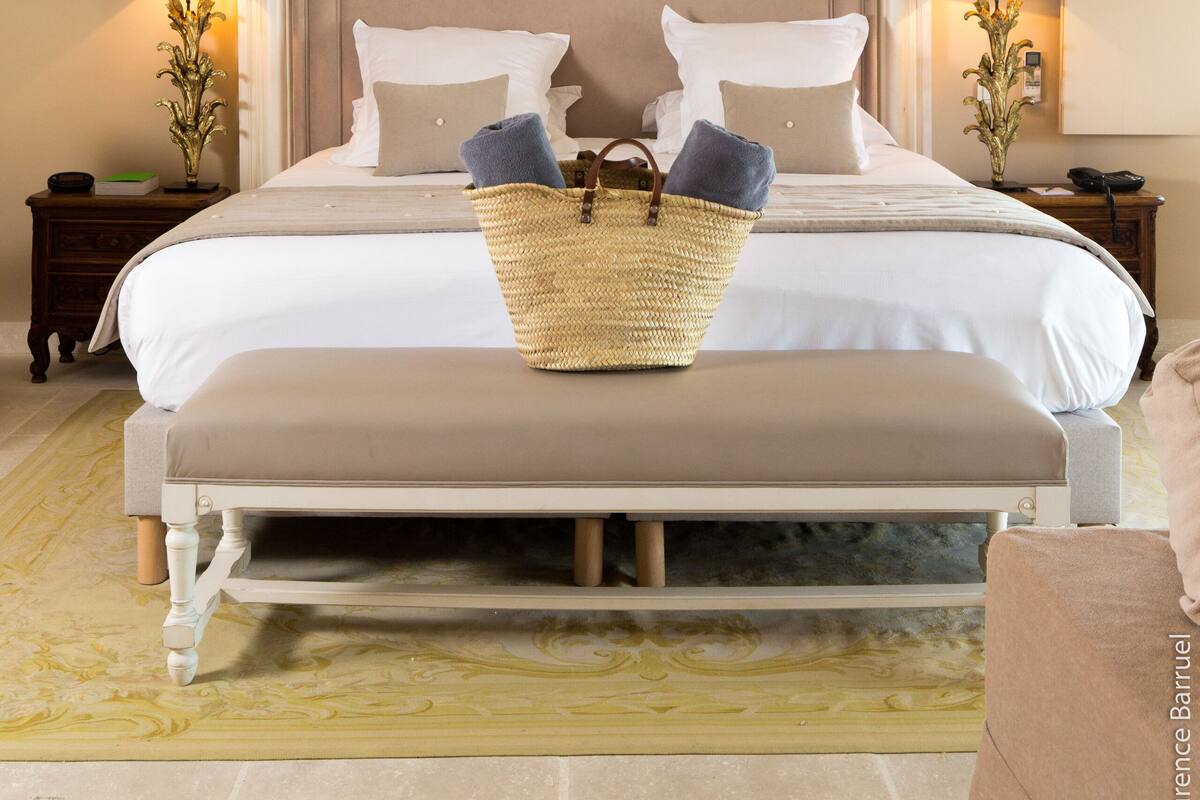 Un dormitorio con una cama grande, un banco y una cesta de toallas.
