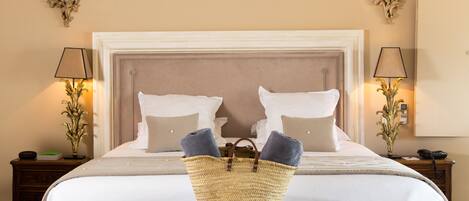A bedroom with a large bed, a bench, and a basket of towels.