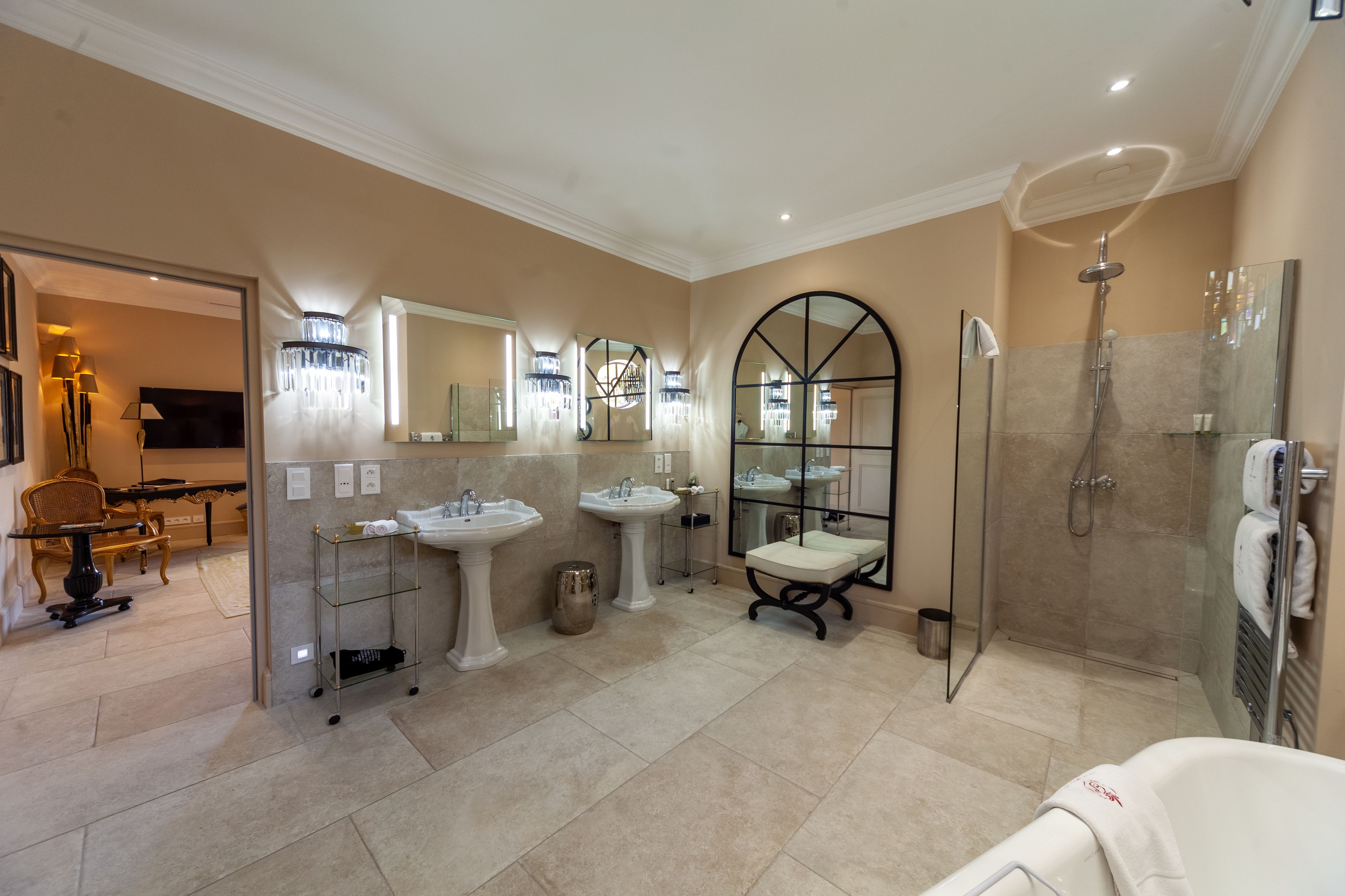 Une salle de bain spacieuse avec trois lavabos, une douche en verre et un grand miroir.