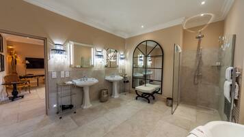 Une salle de bain spacieuse avec trois lavabos, une douche en verre et un grand miroir.
