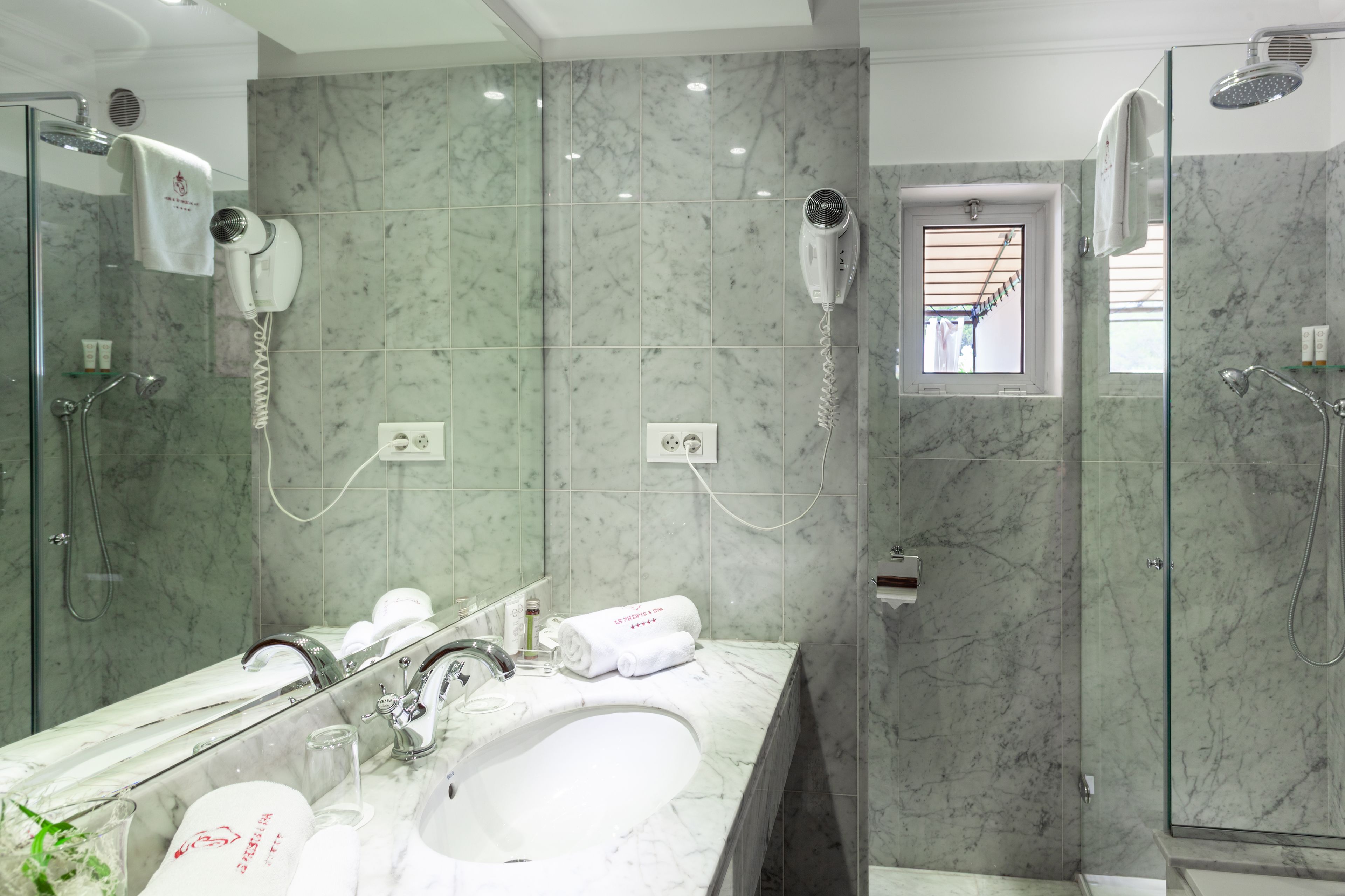 A modern bathroom with a large mirror, a sink, and two hair dryers mounted on the wall.